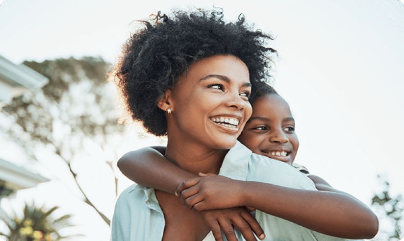 Mother smiling while young daughter hugs her.