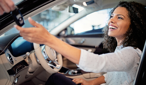 woman sitting in car while someone else hands her keys