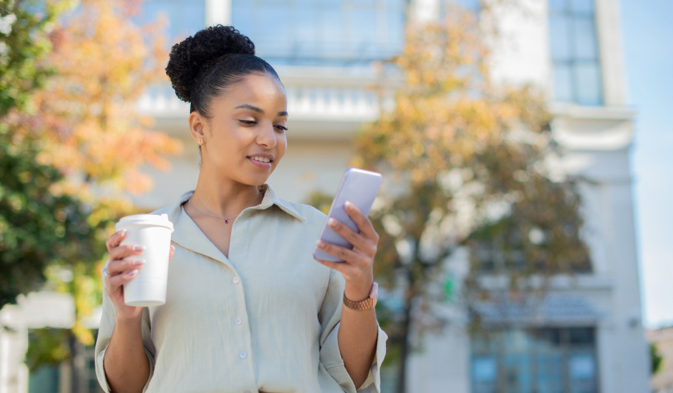 Lady looking at phone with coffee cup