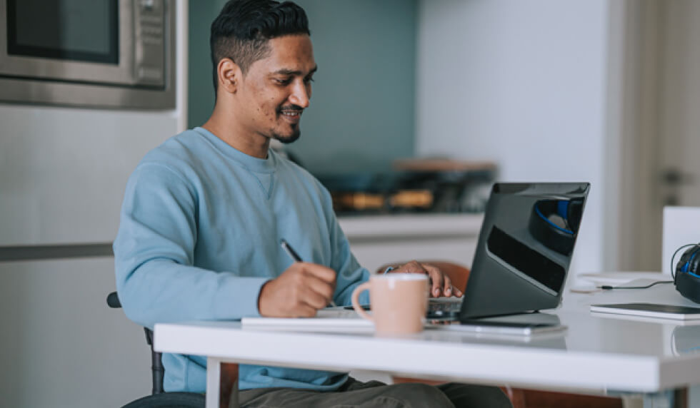 Man at desk with pen and laptop